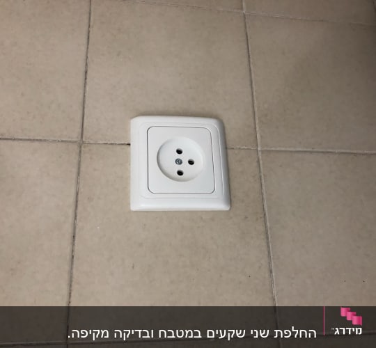 שקע חשמלי לבן מותקן על קיר אריחים